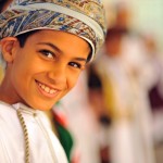 Oman, Muscat, close-up portrait of a cheerful boy in a turban smiling