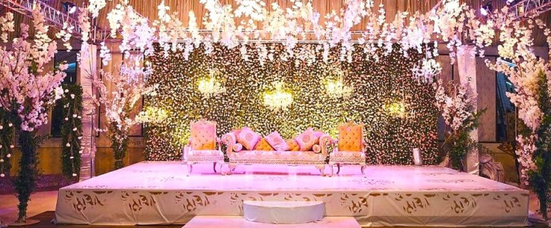 Līgava un līgavainis sēž viesu zālē uz īpaši viņiem dekorētas skatuves